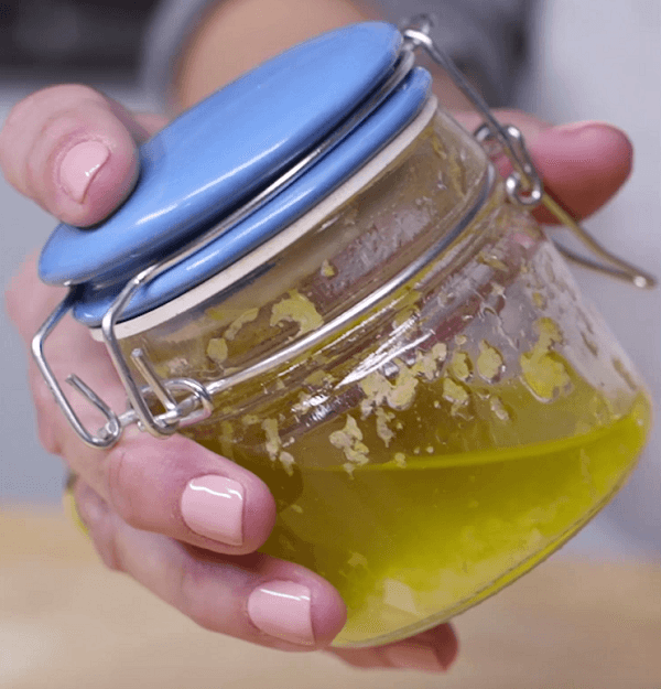 Hands showing a glass jar with ginger and lemon vinaigrette