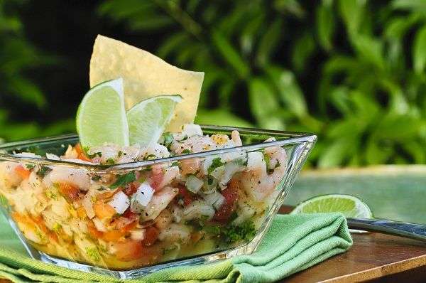  92/5000 Shrimp and octopus ceviche in transparent glass vase on green tablecloth.