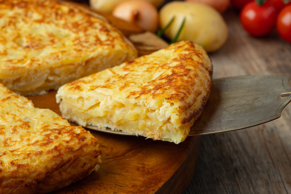 Spanish omelette with potatoes and onion, typical Spanish cuisine. Tortilla espanola. Rustic dark background