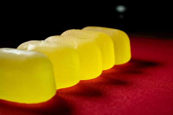 yellow gummy candies on red background close up